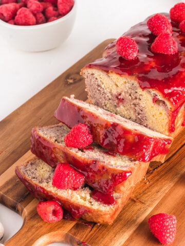 A sliced raspberry marble loaf on a wooden cutting board.