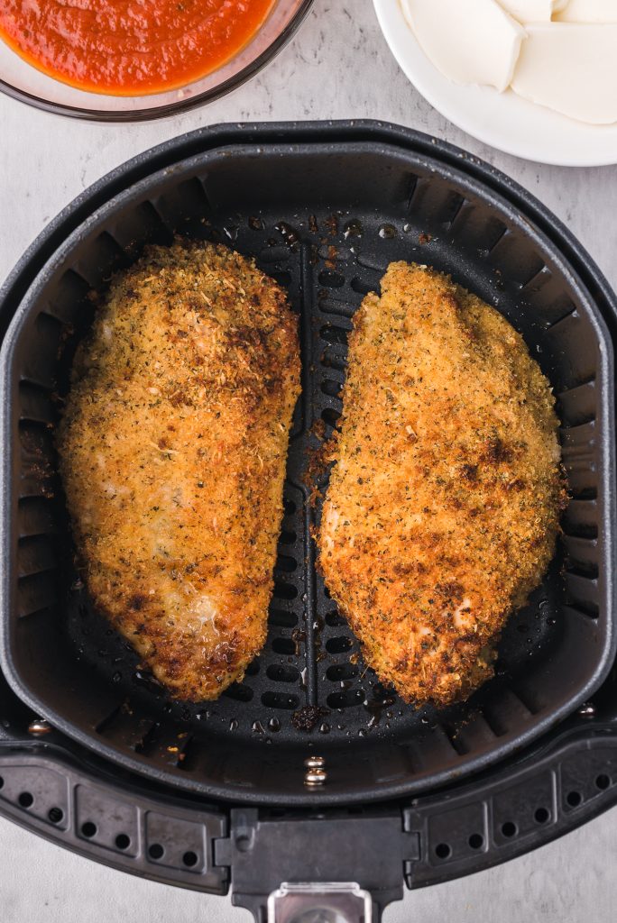 Two pieces of cooked, breaded chicken in an air fryer basket.