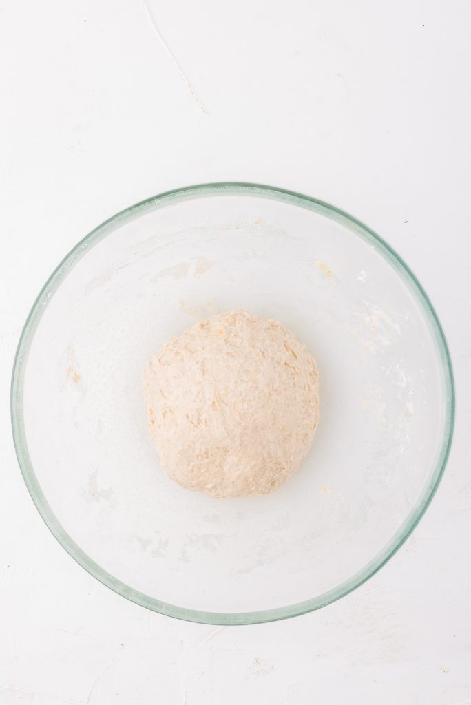 A neat bowl of dough in a glass bowl.