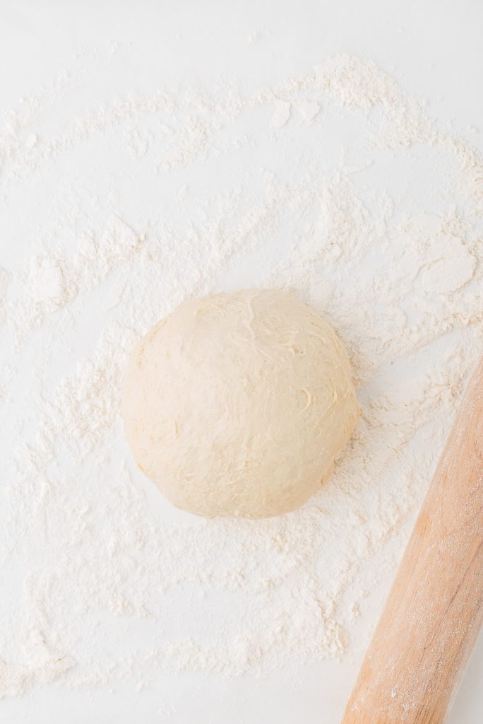 A neat bowl of dough on a floured surface.