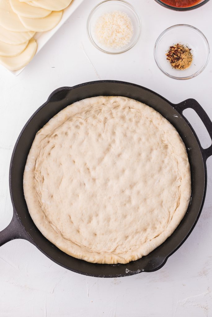 A cast iron pan with the dough set inside and the edge rolled into a crust.