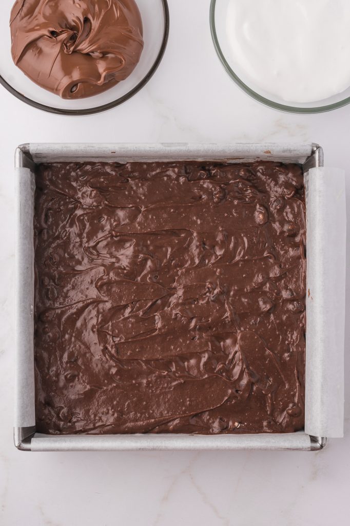 The mixed brownie batter in a parchment lined brownie tray.