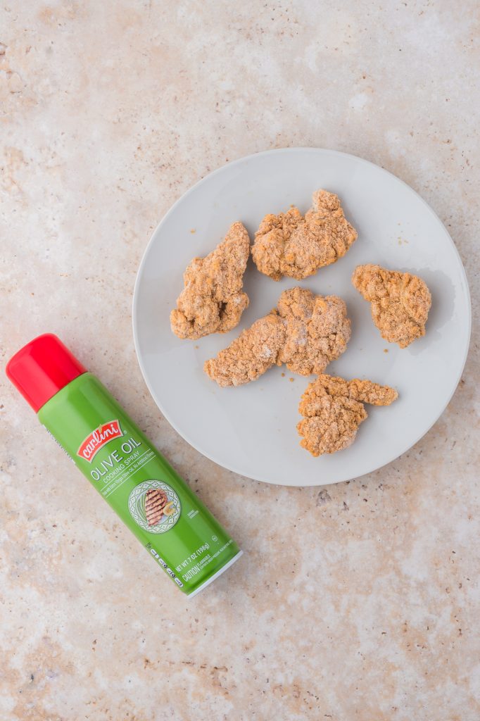 A plate of frozen Air Fryer Frozen Chicken Tenders and a can of cooking oil spray.