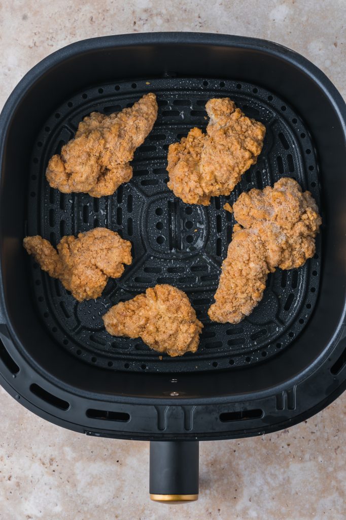 The frozen Air Fryer Frozen Chicken Tenders in the air fryer basket.