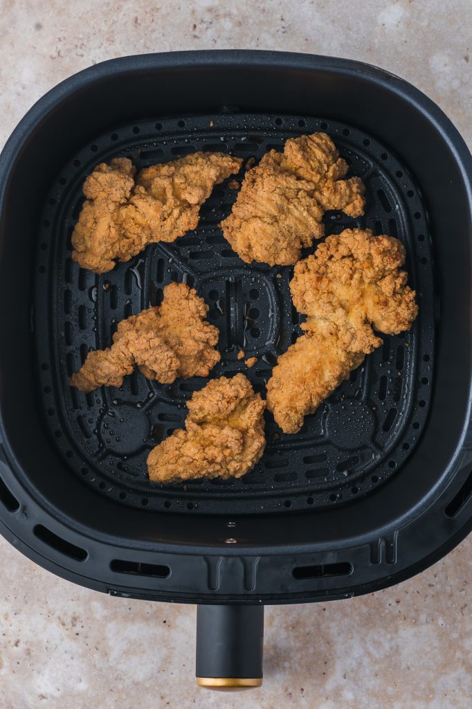 The cooked Air Fryer Frozen Chicken Tenders in the air fryer basket.