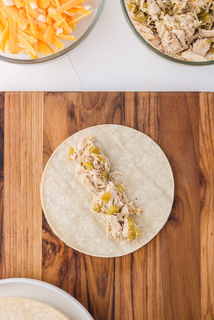 A single tortilla with a column of shredded chicken and chili mixture down the middle.