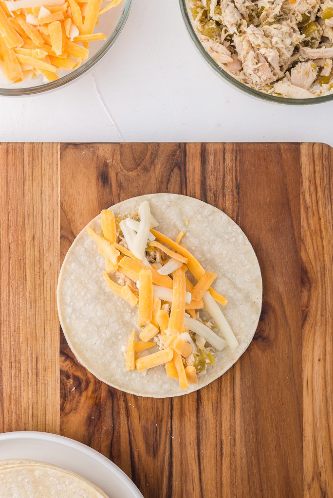 A single tortilla with a column of shredded chicken and chili mixture down the middle, topped with shredded cheese.