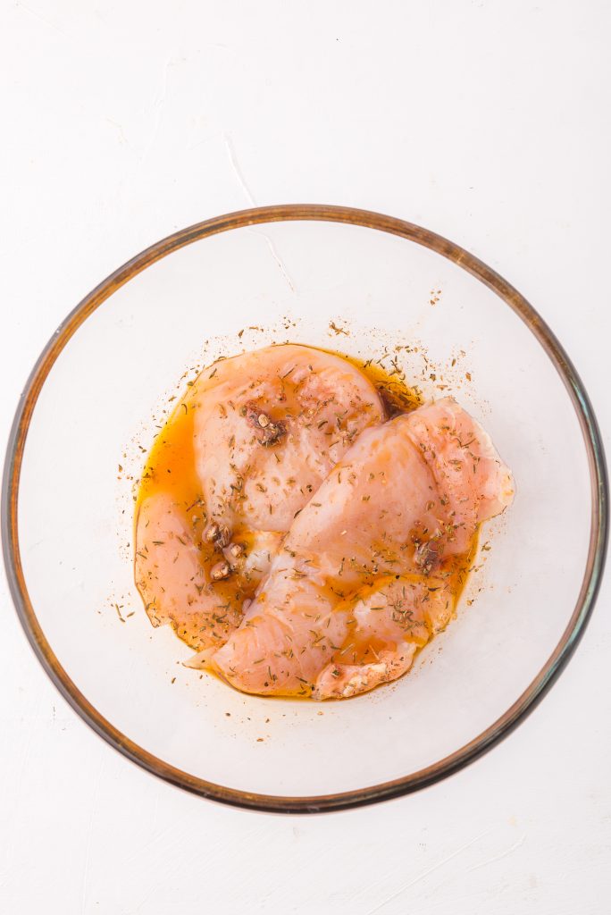 A glass bowl with the raw chicken marinating.