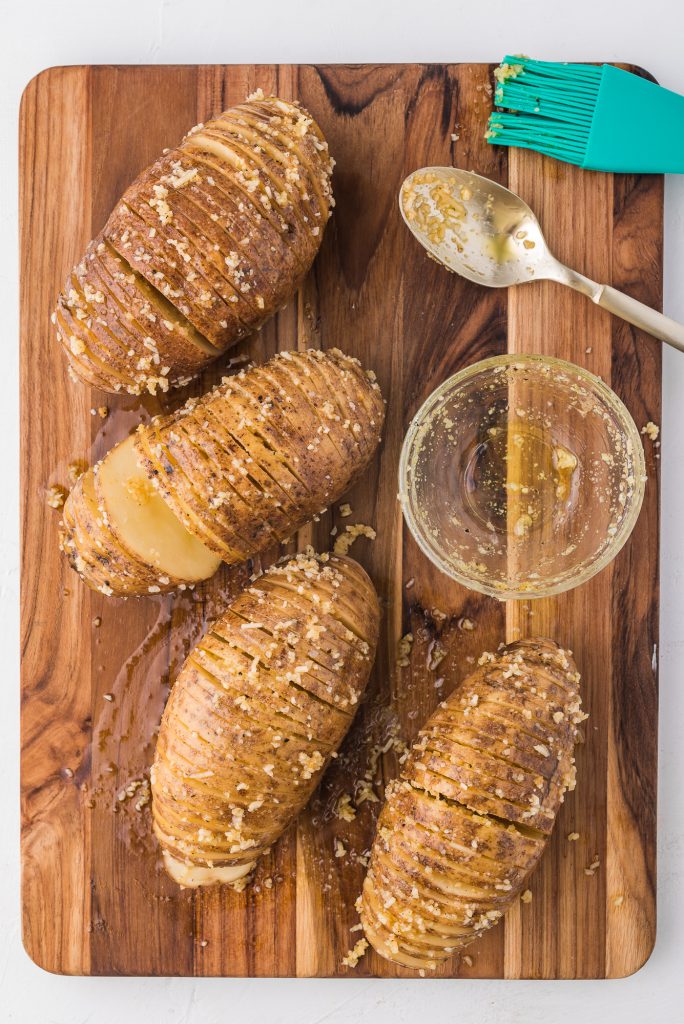 Four sliced potatoes brushed with oil and toppings.