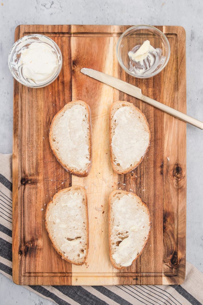 Buttered slices of bread on a wooden cutting board.