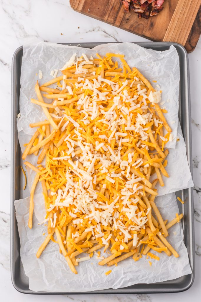 A pan of cooked frieds topped with cheese.