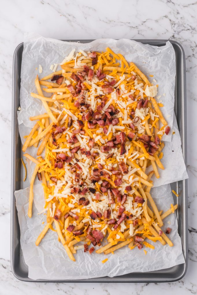 A pan of cooked fries topped with cheese and bacon.