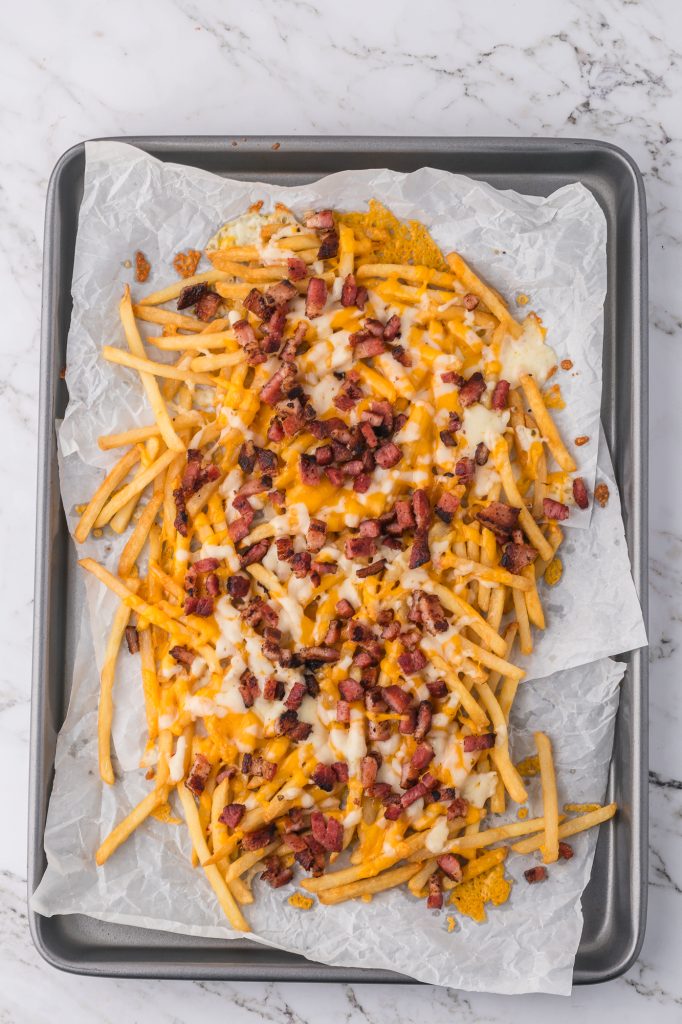 A pan of cooked fries topped with cheese and bacon.