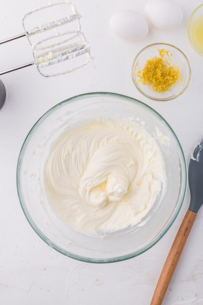 A mixture of softened cream cheese and sugar in a glass bowl.