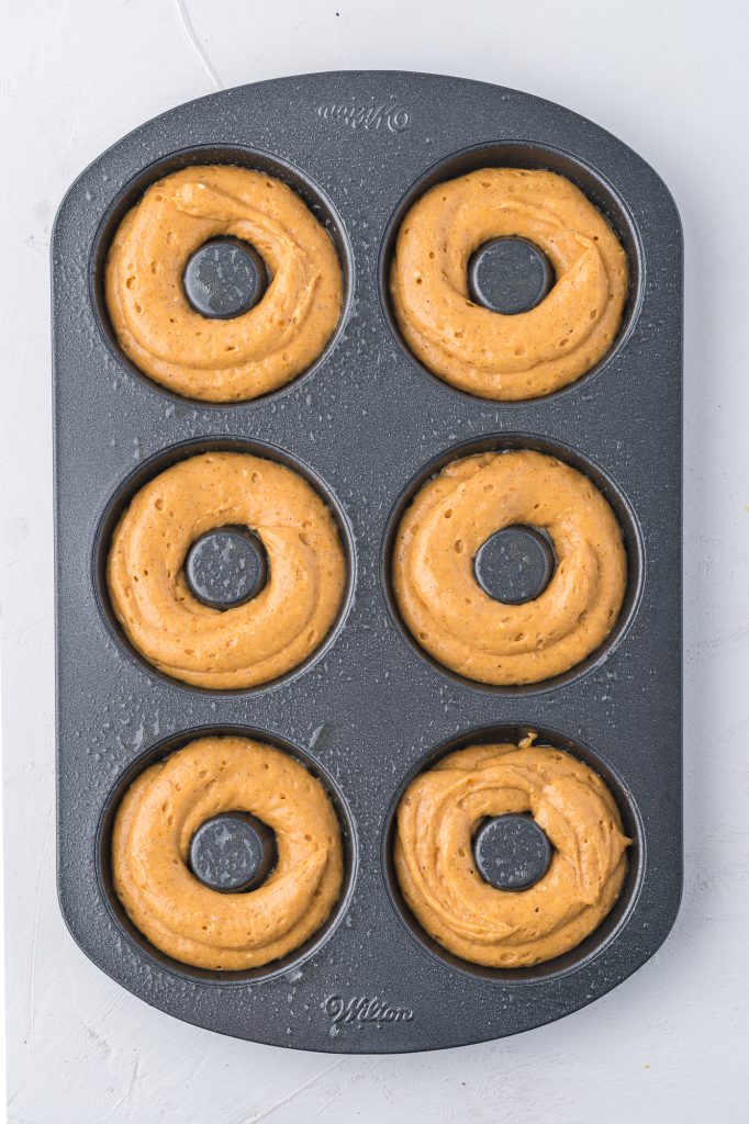 A donut pan piped with six donut batters.