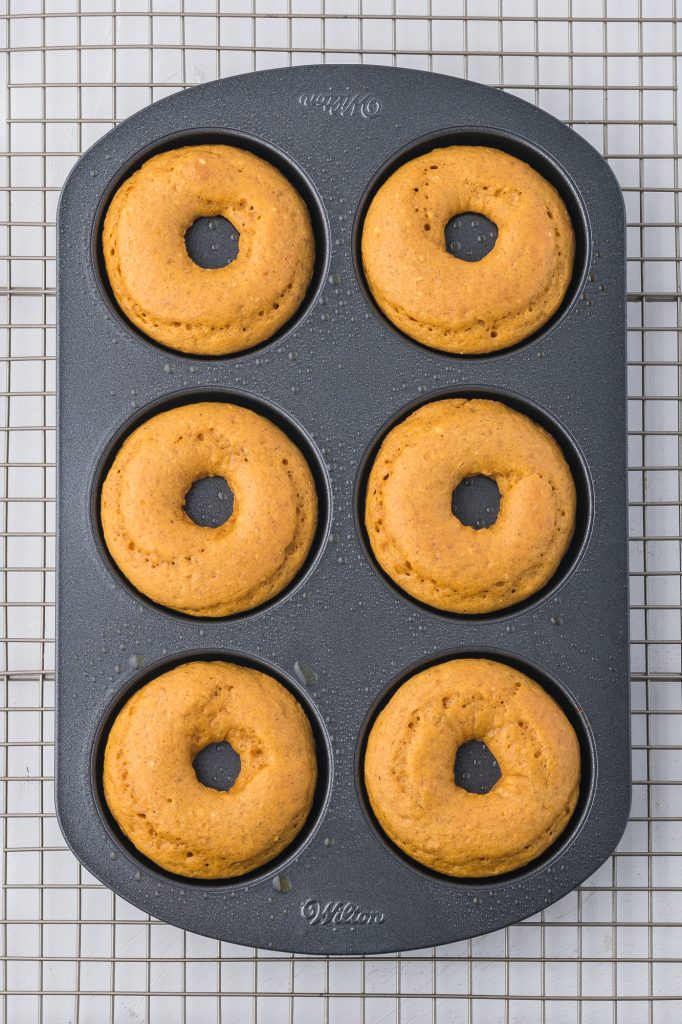 Six donuts in a donut pan right out of the oven.