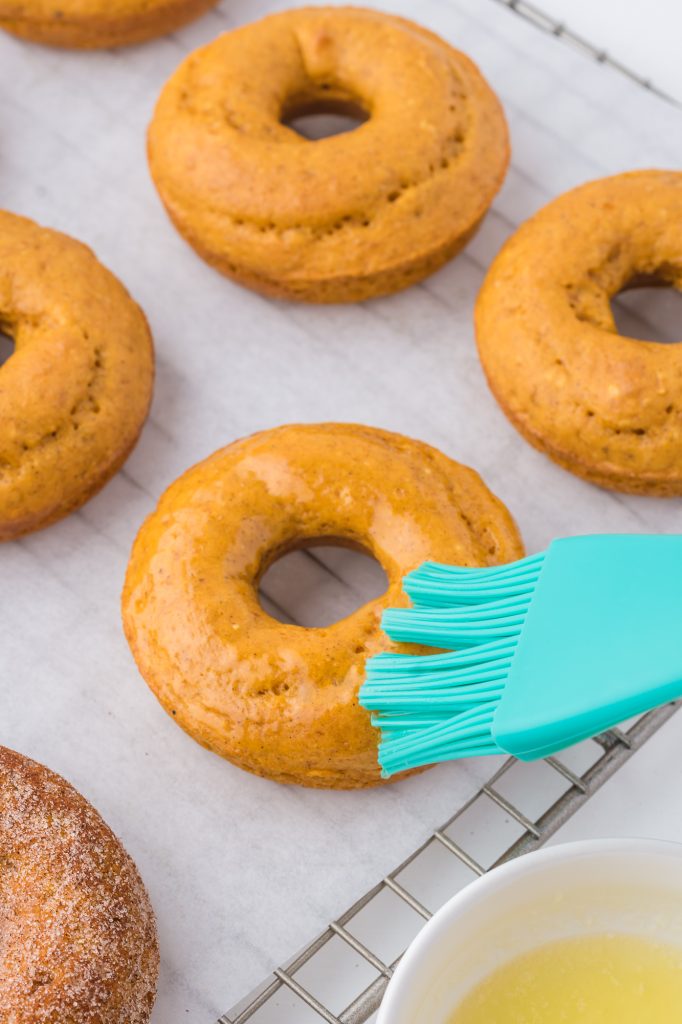 A donut being brushed with a glaze.