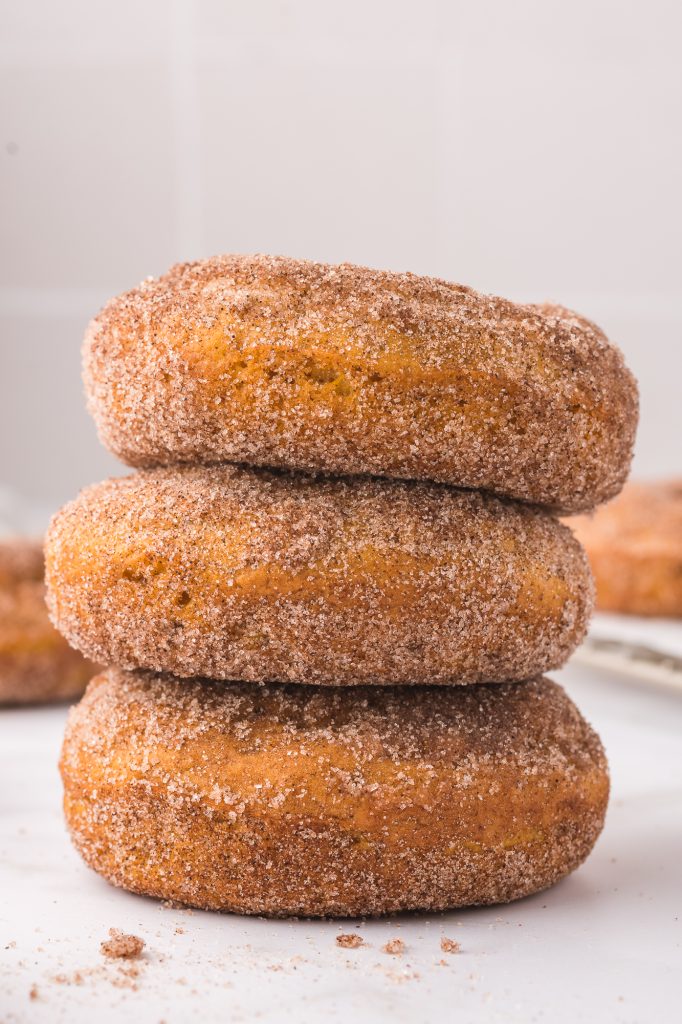 A stack of three cinnamon sugar pumpkin donuts.