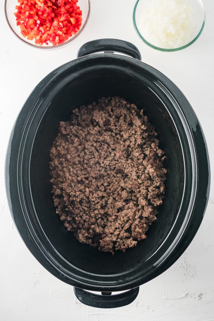 Cooked ground beef at the bottom of a slow cooker.