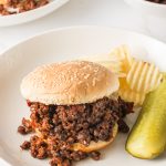 A plated sloppy joe served with chips and a pickle.