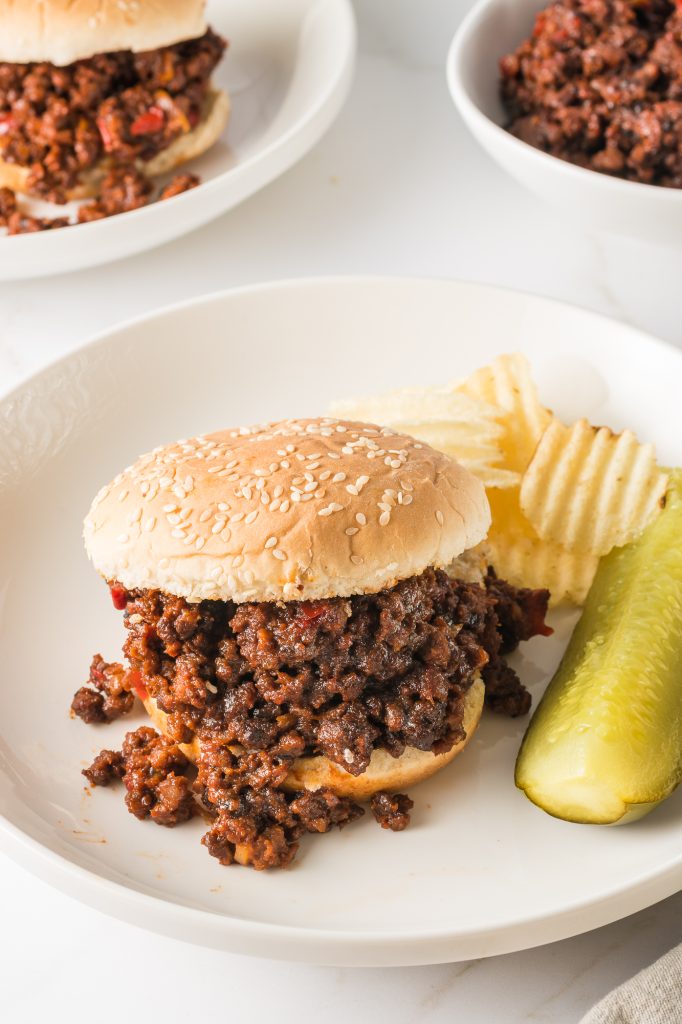 A plated sloppy joe served with chips and a pickle.