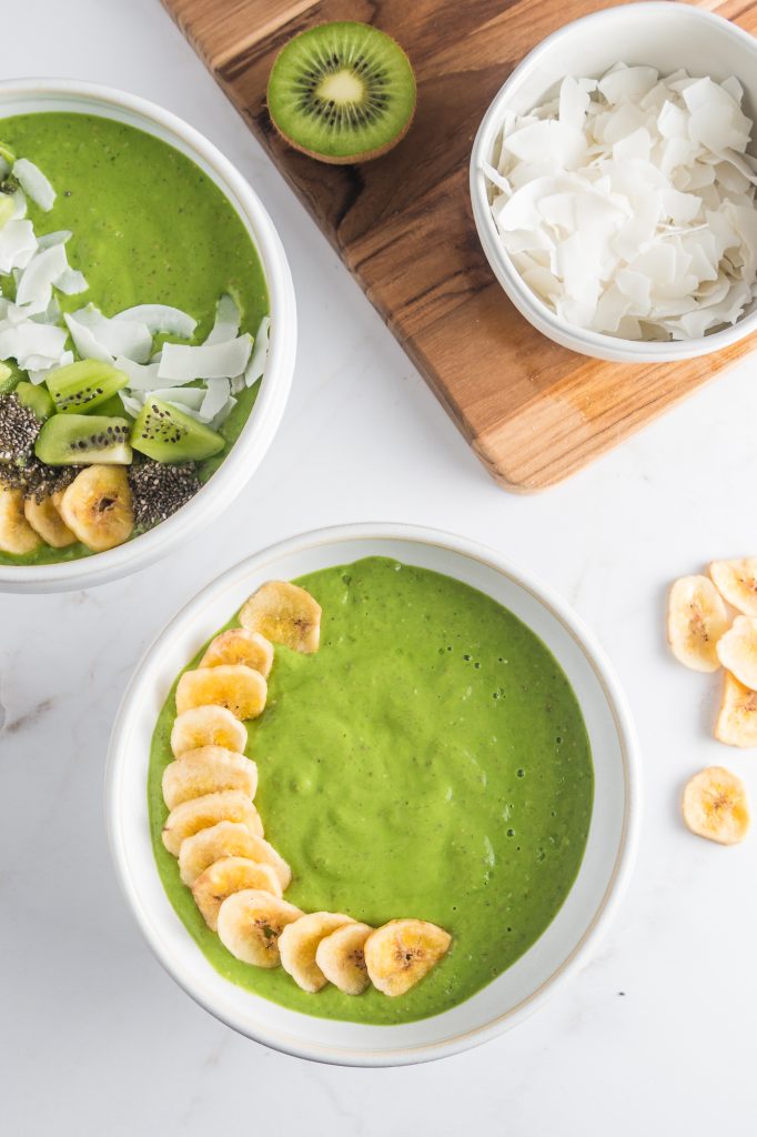 A white bowl full of the Tropical Green Smoothie Bowl base topped with bananas.