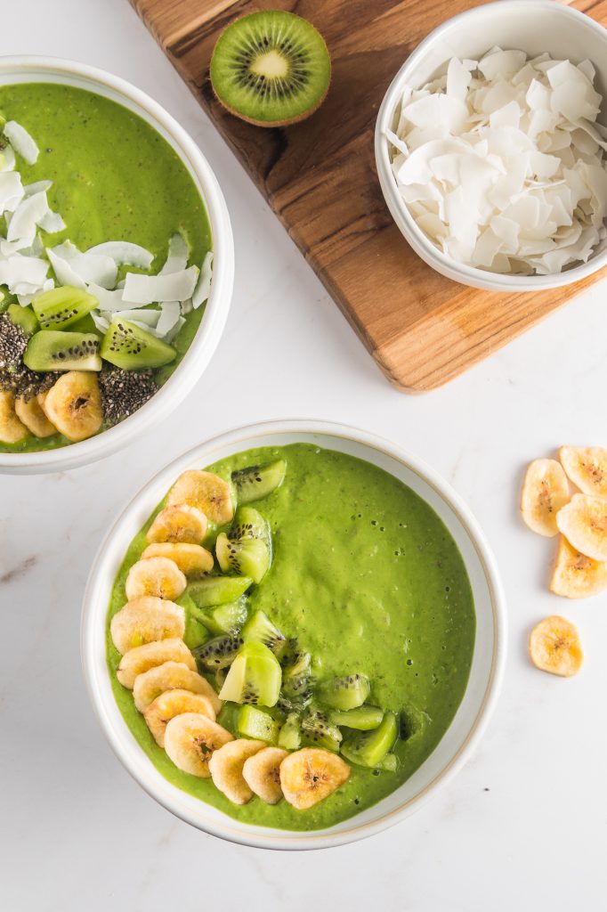 A white bowl full of the Tropical Green Smoothie Bowl base topped with bananas and kiwi.