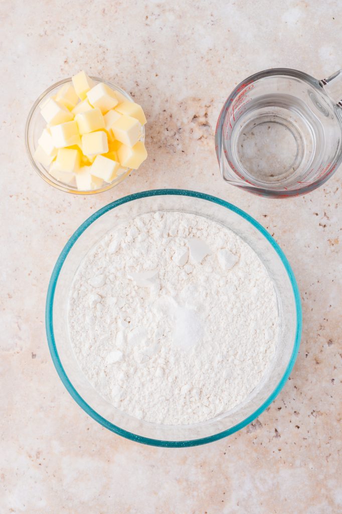 Three bowls containing flour, butter, and water.