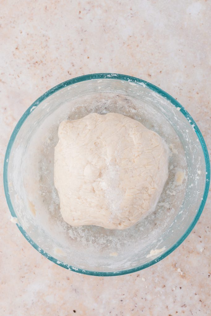 A bowl with a ball of formed dough in it.