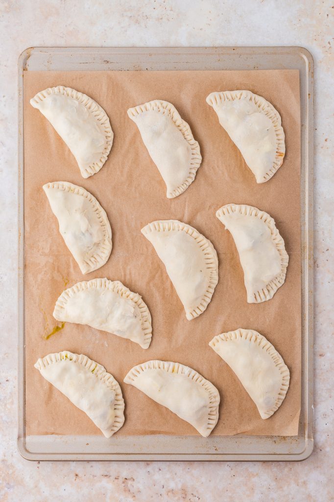 A baking sheet of raw Caprese Empanadas.