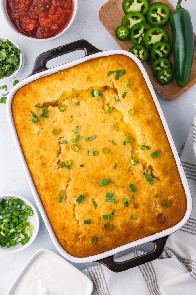 The finished Jiffy Mexican Cornbread Casserole in a casserole dish with sliced green onion and cilantro on top.