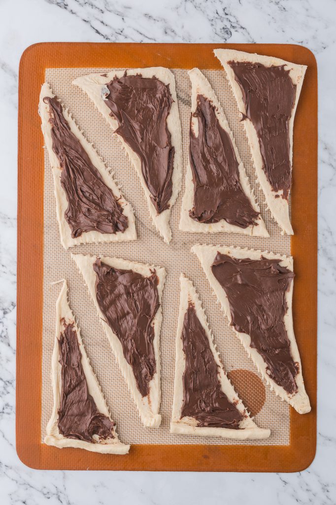 Eight raw dough triangles spread with Nutella spread.