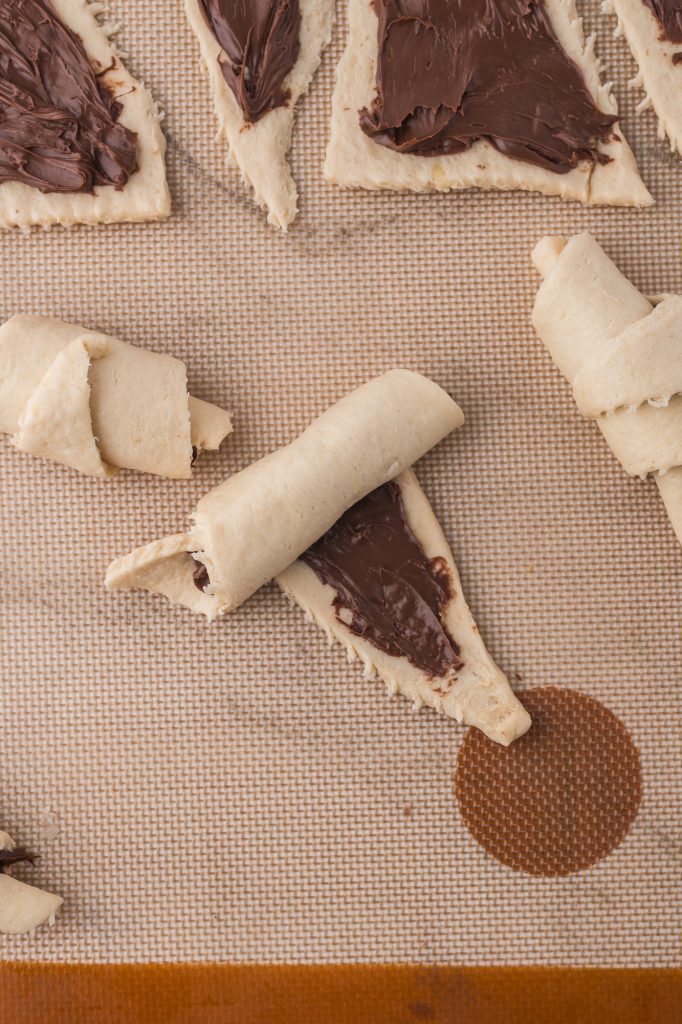 A raw Nutella Croissant crescent getting rolled up.