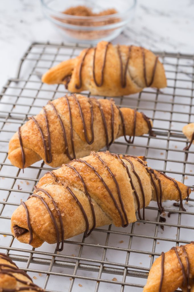 Nutella-drizzled Nutella Croissants on a metal cooling rack.