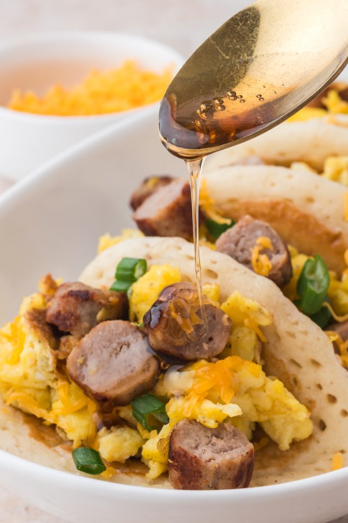 A close up of a spoon pouring some maple syrup over a Pancake Taco.