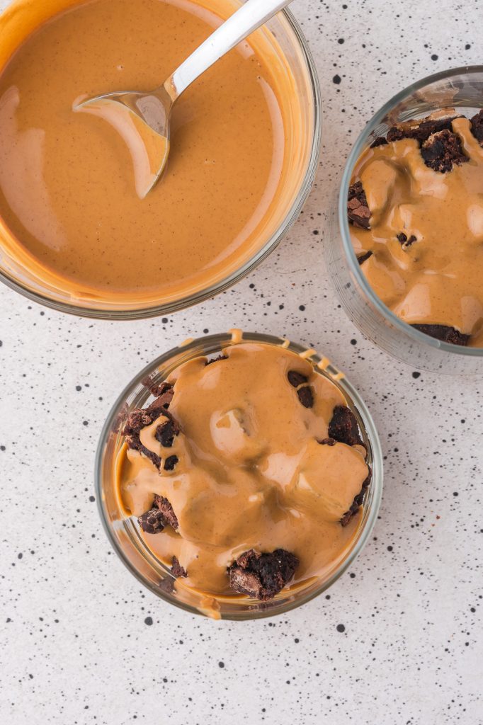 Two bowls of brownie chunks covered in warm peanut butter next to a bowl of peanut butter.