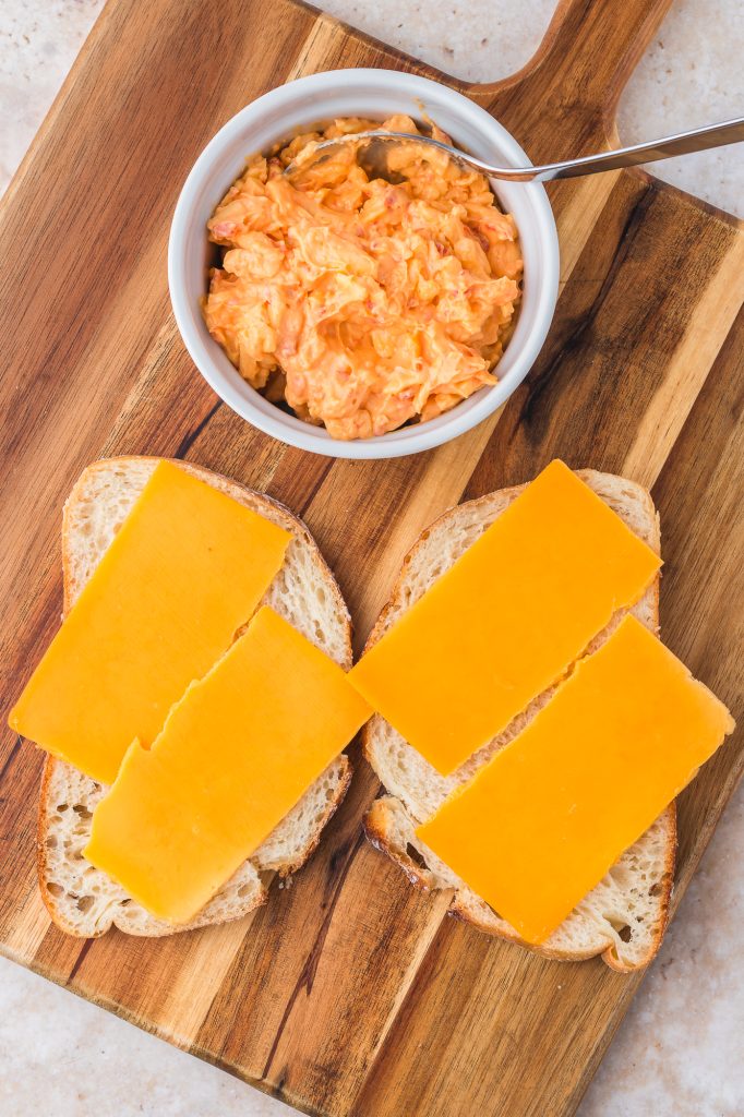 Two slices of bread with slices of sharp cheddar cheese on top.