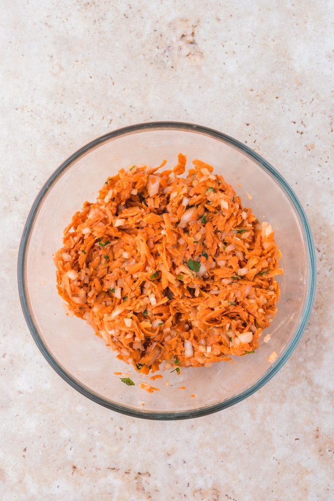 All the ingredients for the Sweet Potato Fritters combined in a glass bowl.