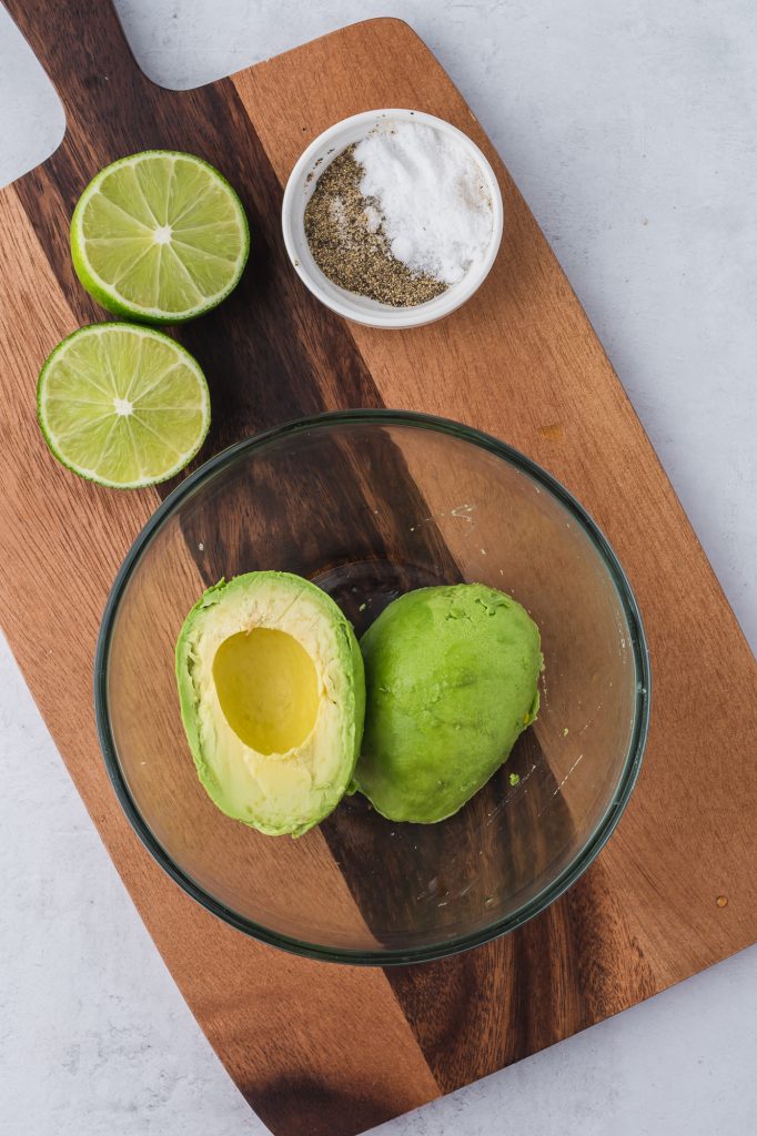 An avocado sliced in half in a glass bowl.