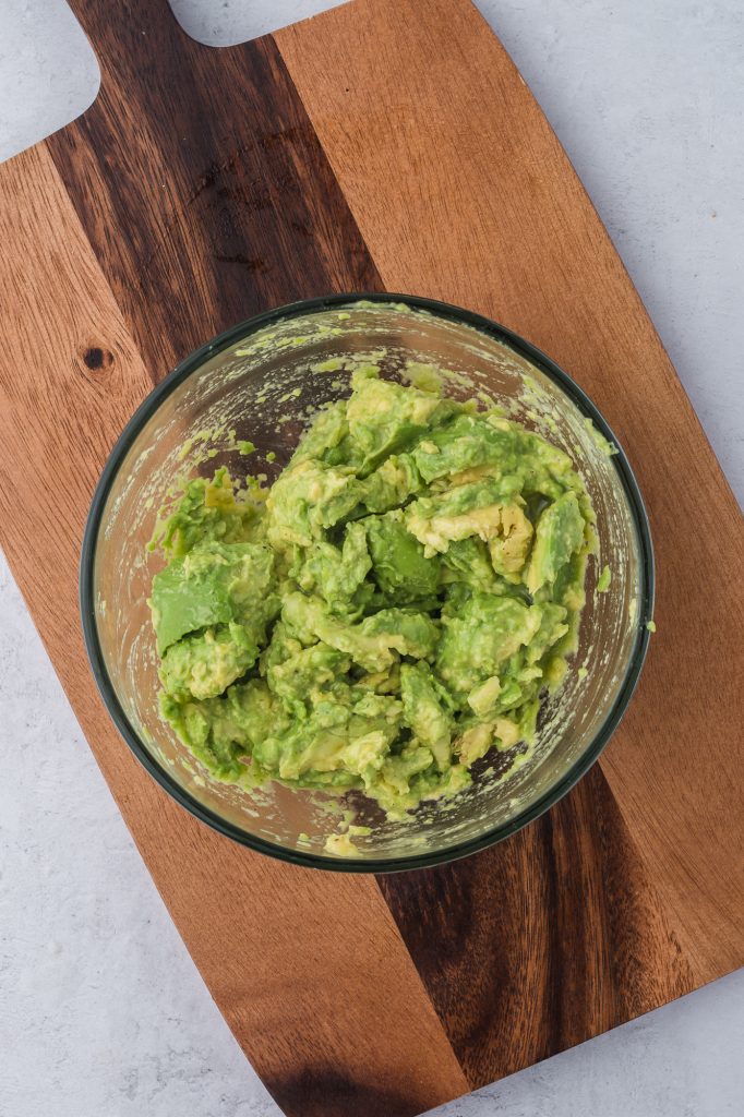 A mashed avocado in a glass bowl.