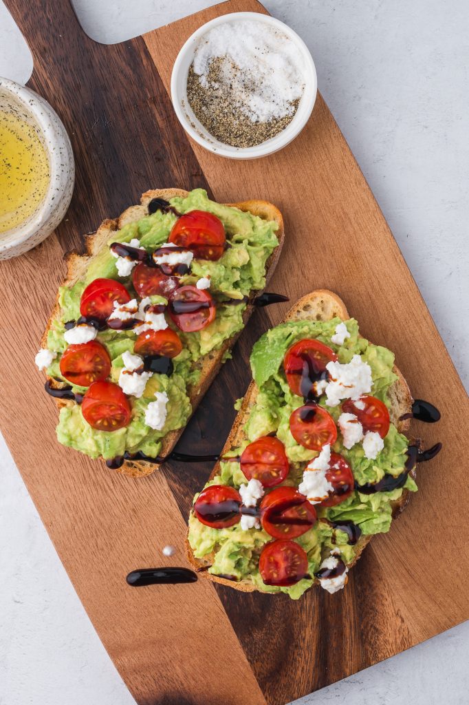 Two slices of Avocado Toast with Tomato topped with feta cheese.