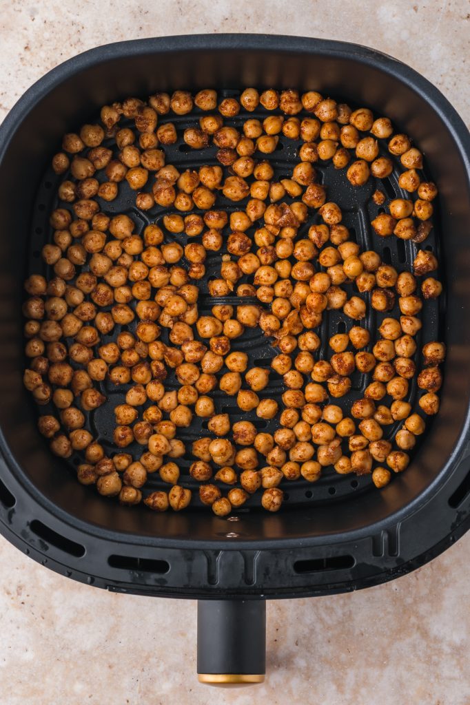 All the mixed ingredients for Crispy Air Fryer Chickpeas in the basket of an air fryer.