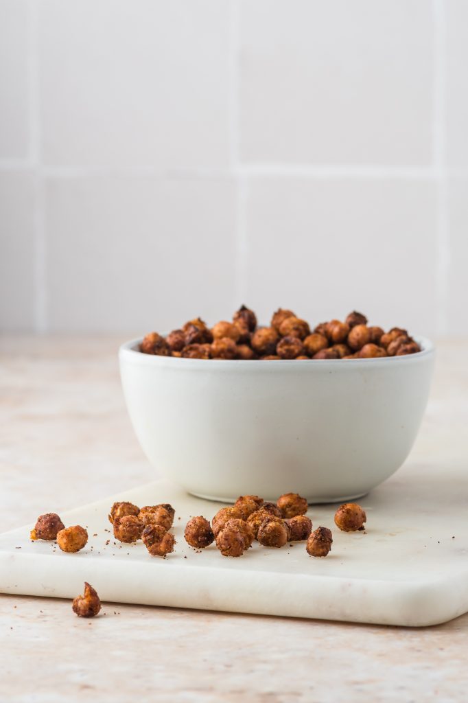 A bowl full of Crispy Air Fryer Chickpeas with some stray chickpeas strewn around it.