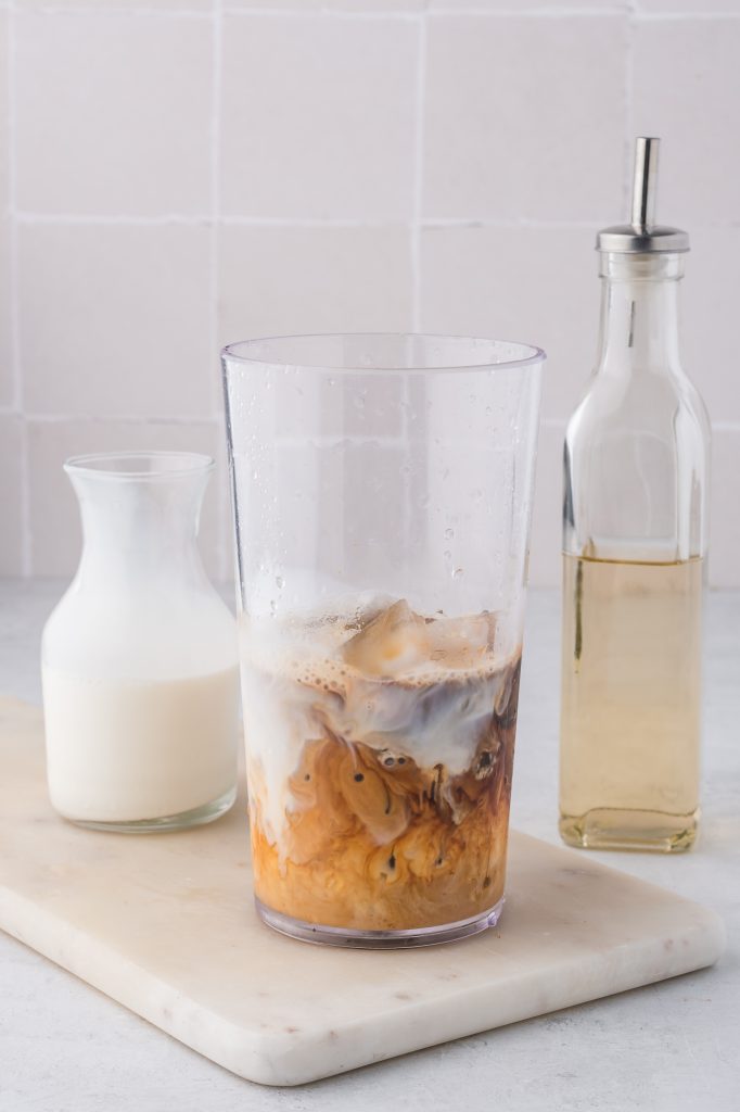 The bottom half of a shaker with espresso, milk, and sweetener for Double Shot Iced Shaken Espresso.