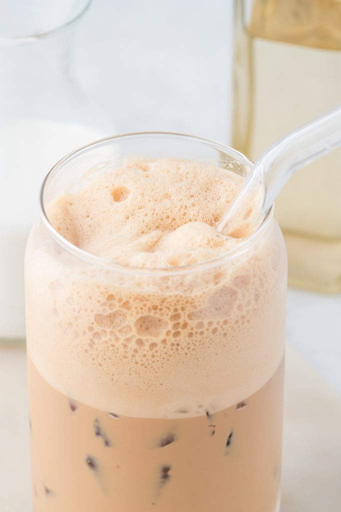 A close-up of a clear glass of Double Shot Iced Shaken Espresso with a glass straw.