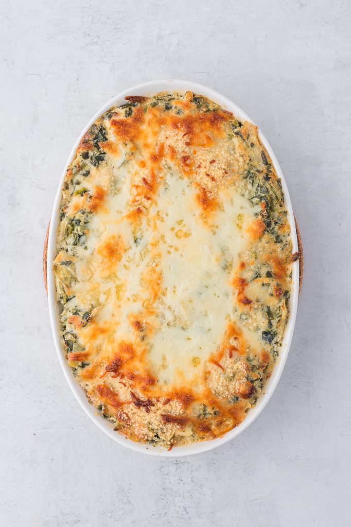 The baked No Mayo Spinach Artichoke Dip spread in a casserole dish.