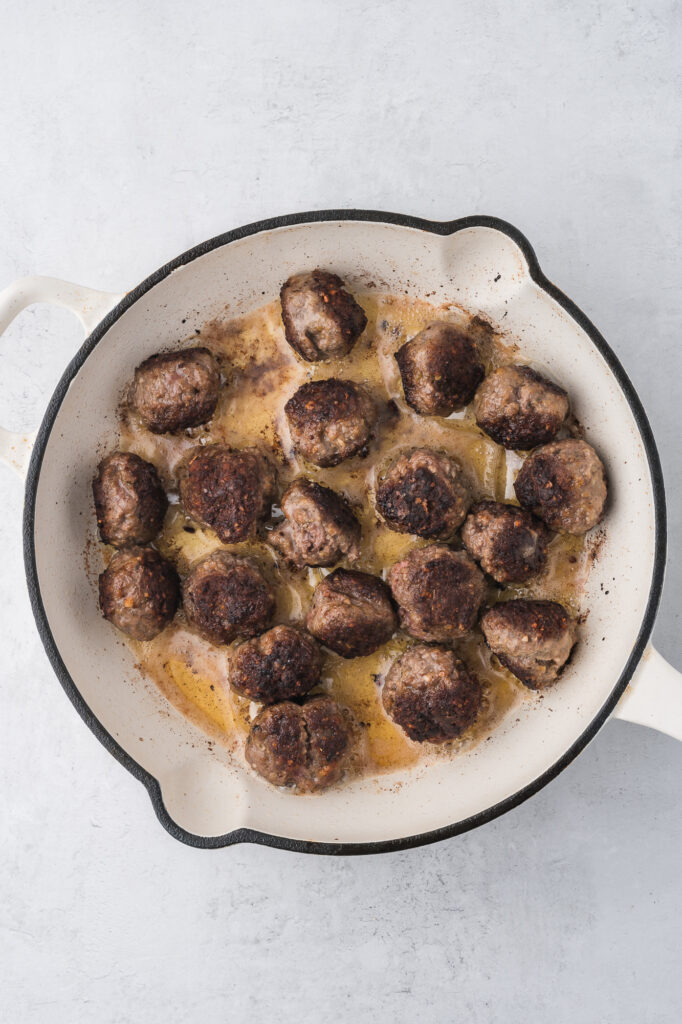 The cooked meatballs in a large skillet.