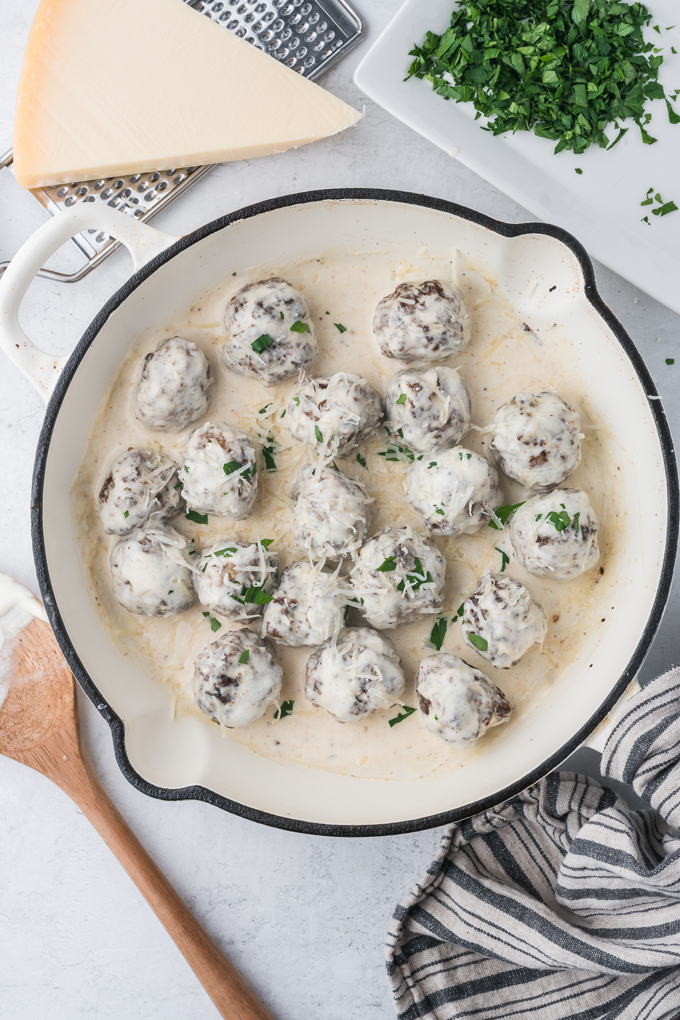 The Alfredo sauce covering the meatballs in the large skillet.