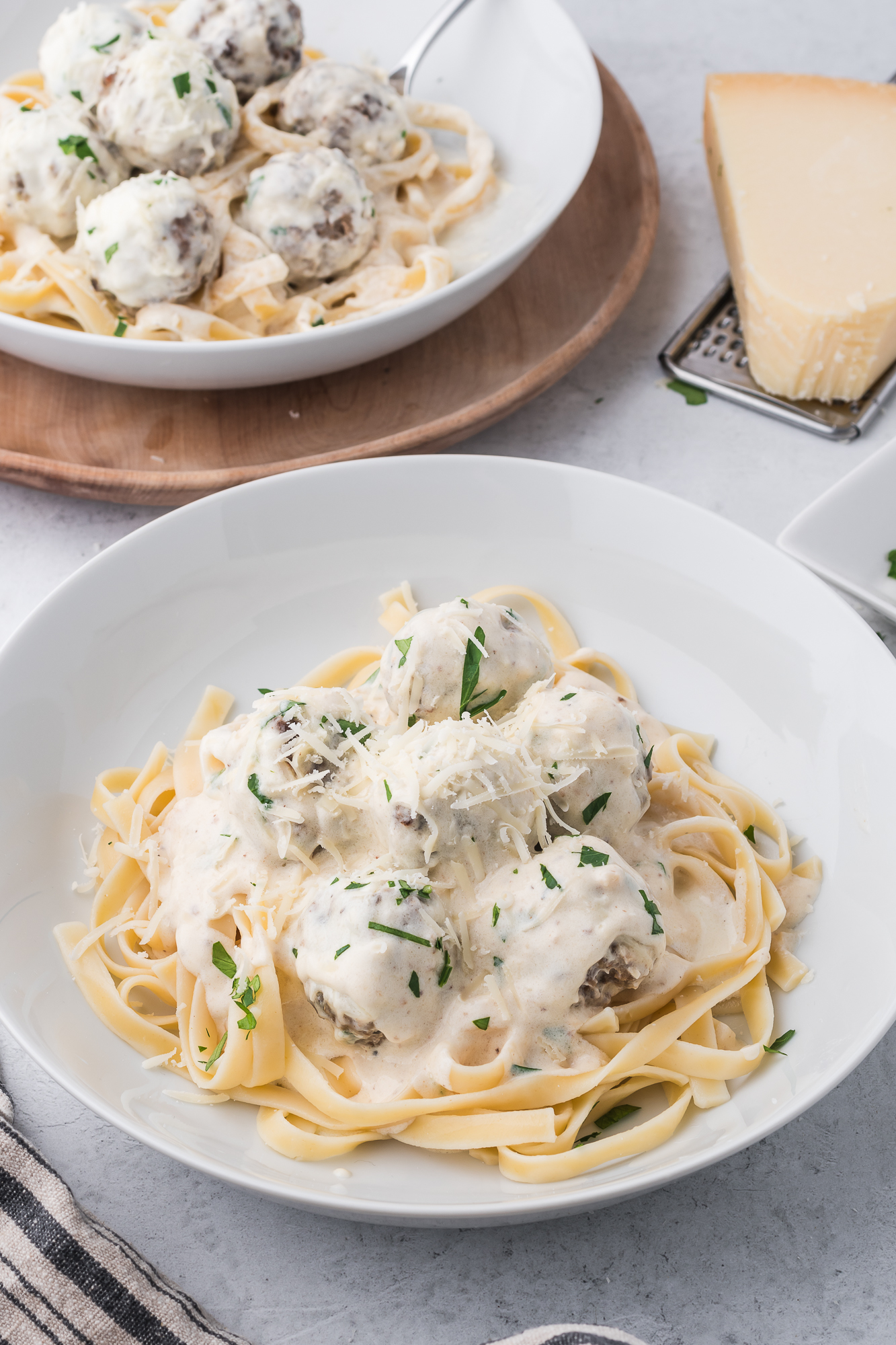 The Alfredo and Meatballs placed on a bed of fettuccine in a white bowl.