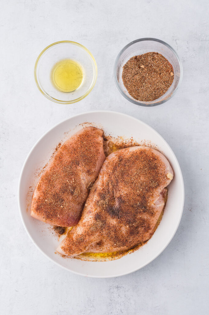 Two chicken breasts coated with the blend of spices for Baked Chicken Tacos with Avocado Lime Crema.